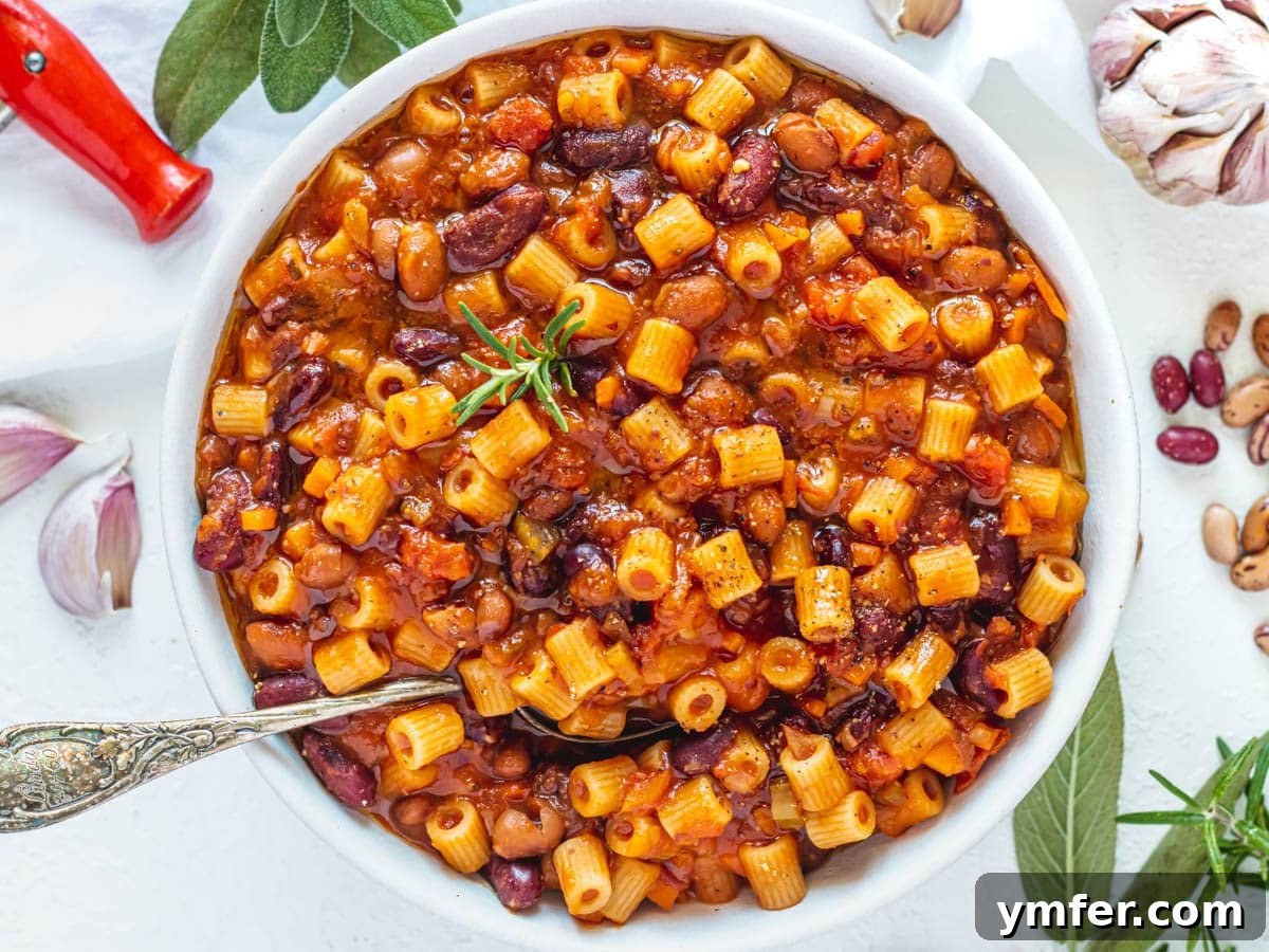 Hearty Chickpea Pasta 10 A bowl of heartwarming Pasta e Fagioli, garnished with a silver spoon and garlic cloves.