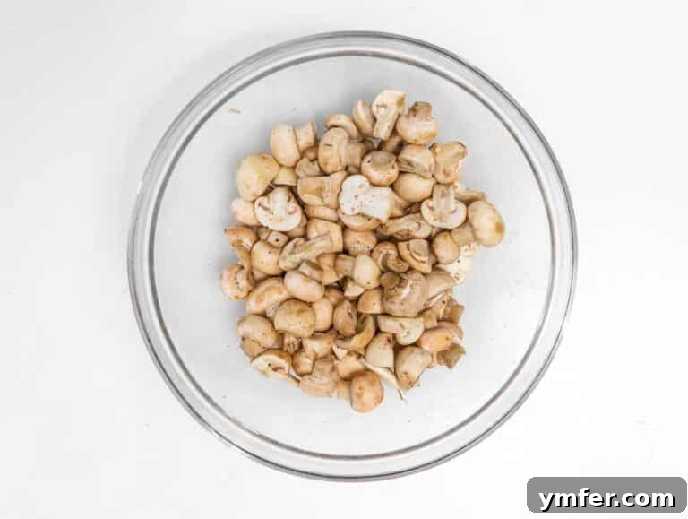 Crispy Air-Fried Mushrooms 5 Mushrooms coated in olive oil, salt, and pepper in a mixing bowl.