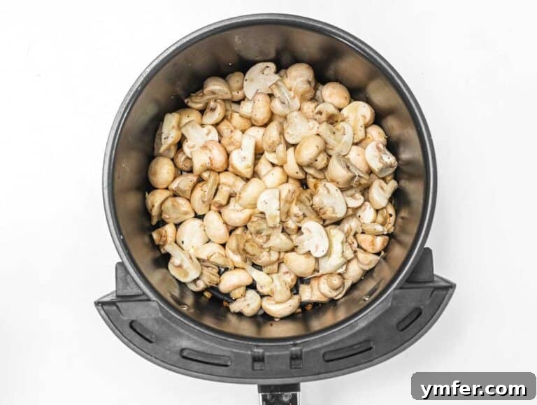 Crispy Air-Fried Mushrooms 6 Mushrooms cooking in an air fryer basket, halfway through the process.