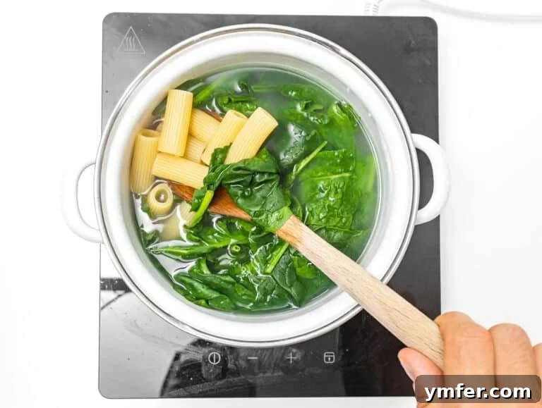 Zesty Lemon Ricotta Pasta 9 Rigatoni pasta cooking with spinach.