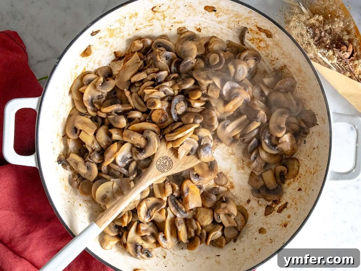 Golden Garlic Mushrooms 9 sauteed mushrooms in a white skillet with a wooden spoon