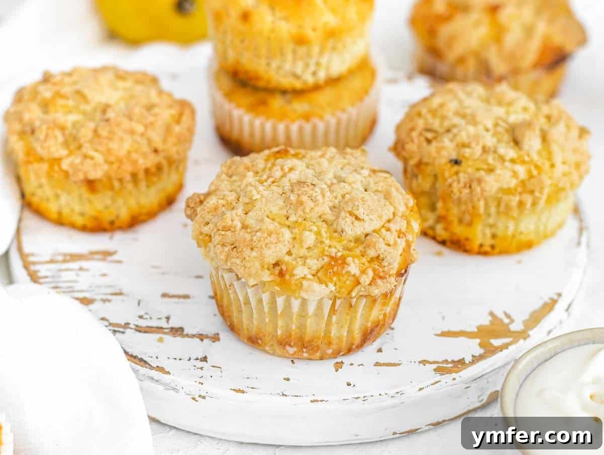 Two soft lemon muffins, one plain and one with streusel topping, on a wooden board.
