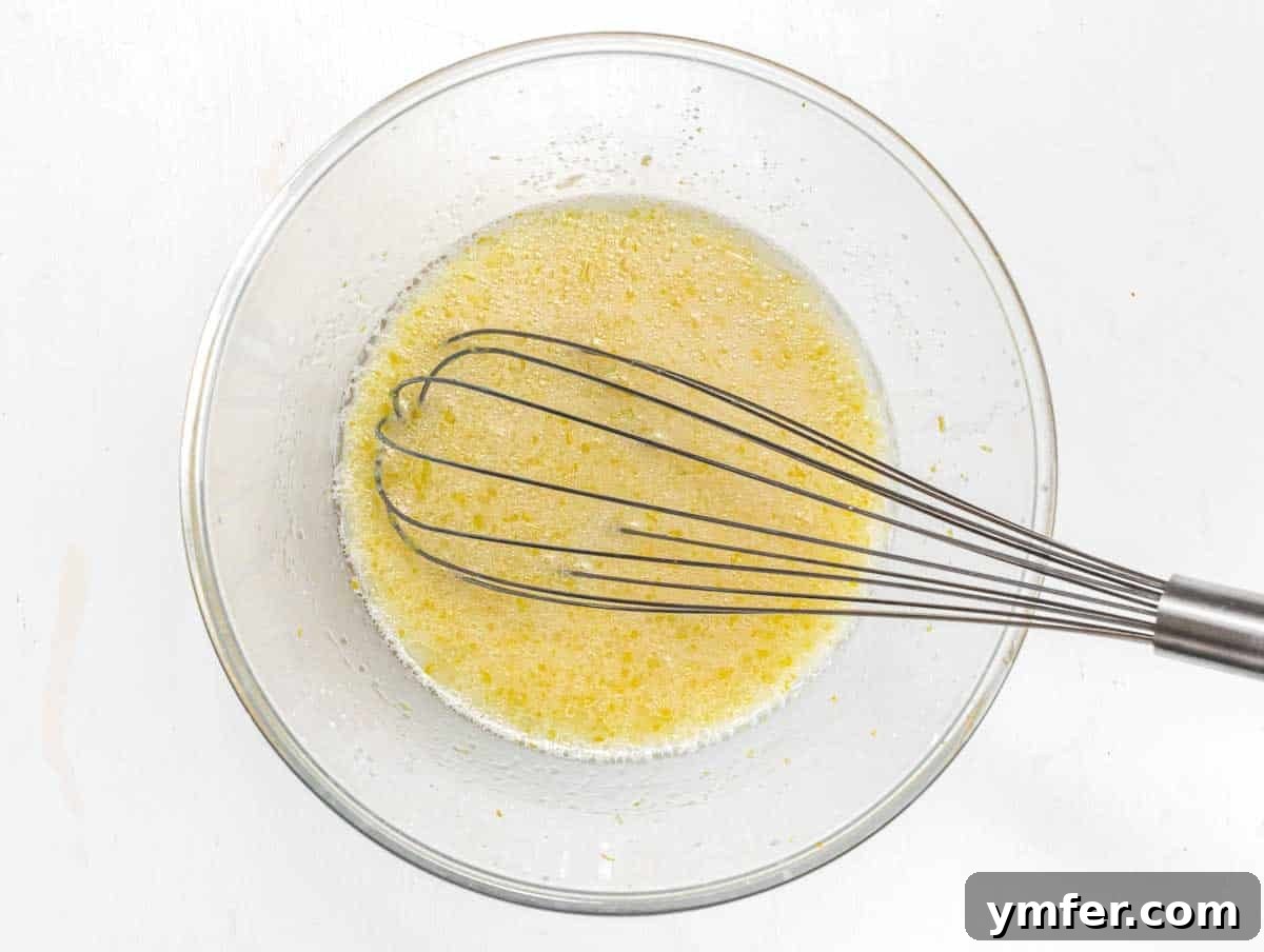 Wet ingredients for muffin batter being whisked in a bowl.