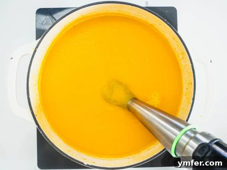Golden Ginger Carrot Elixir 18 carrot soup in a casserole with a hand mixer