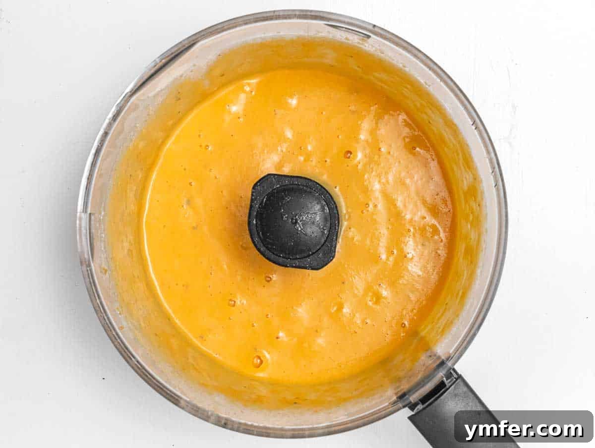 Golden Harvest Pumpkin Pasta 9 Close-up of the smooth, vibrant orange pumpkin sauce in a food processor bowl after blending.
