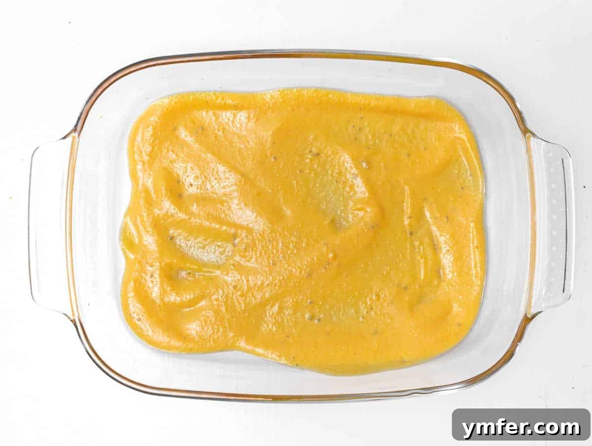 Golden Harvest Pumpkin Pasta 10 A thin layer of pumpkin ricotta sauce spread across the bottom of a rectangular baking pan.