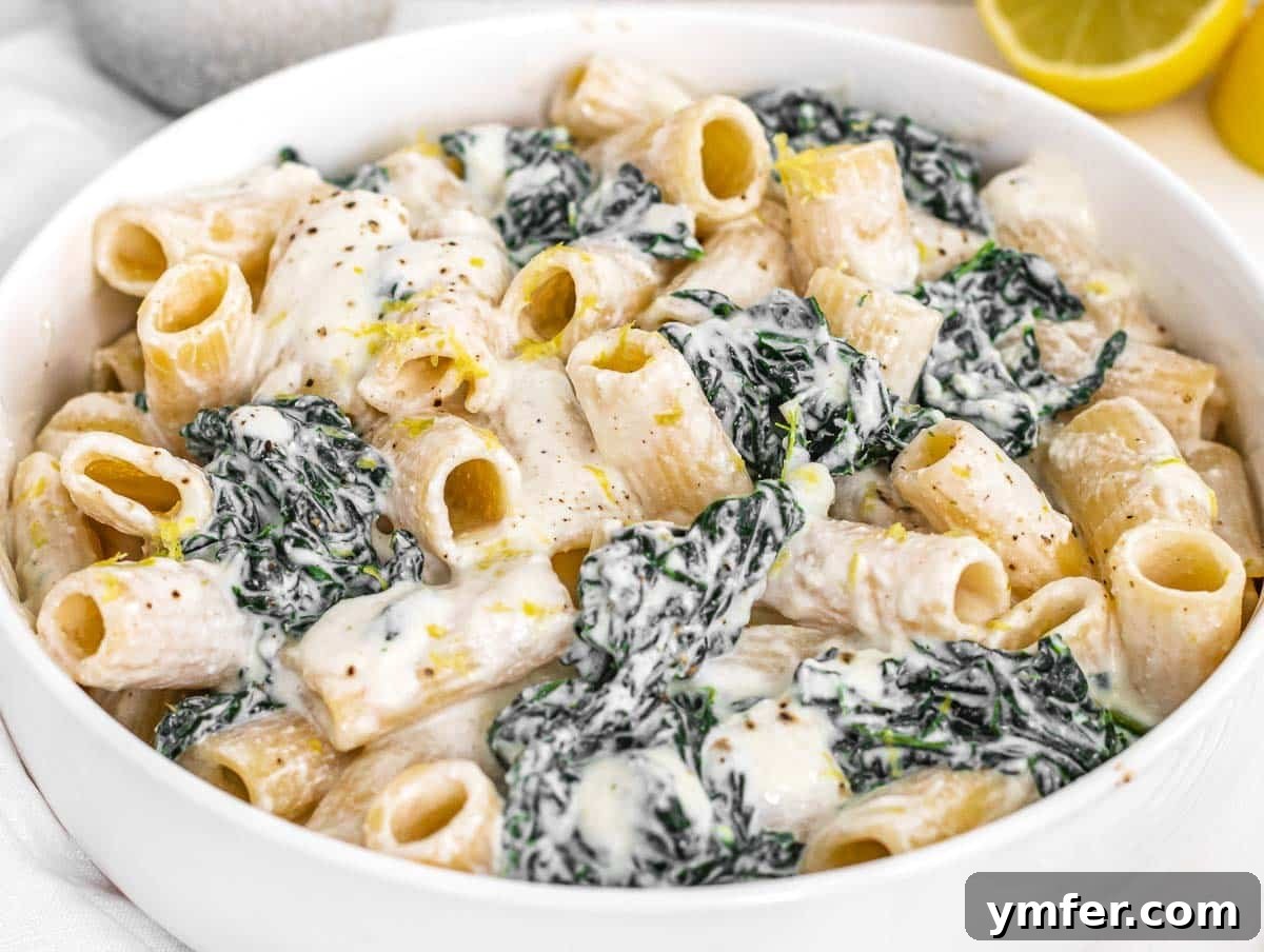 Royal Spire Sweet 3 Creamy Kale Pasta in a white bowl with lemon slices and parsley garnish
