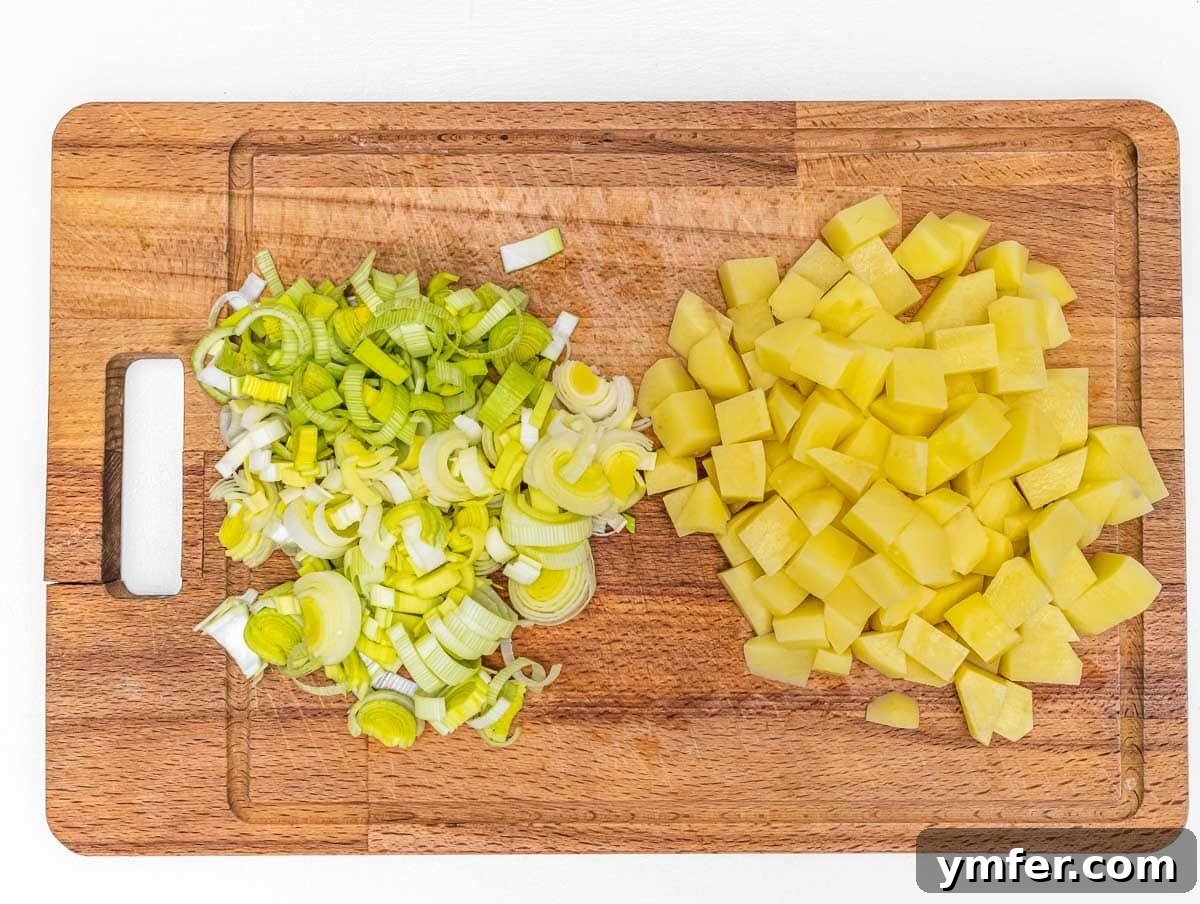 Vegan Potato Frittata 5 Freshly chopped potatoes and sliced leeks arranged on a wooden cutting board.