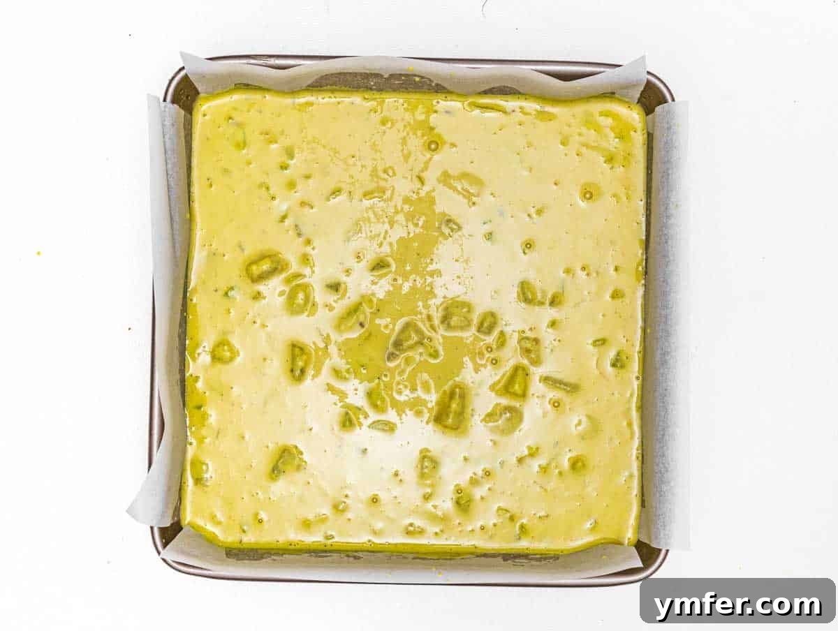 Vegan Potato Frittata 9 Unbaked frittata batter with potato and leek spread evenly in a parchment-lined square baking pan.
