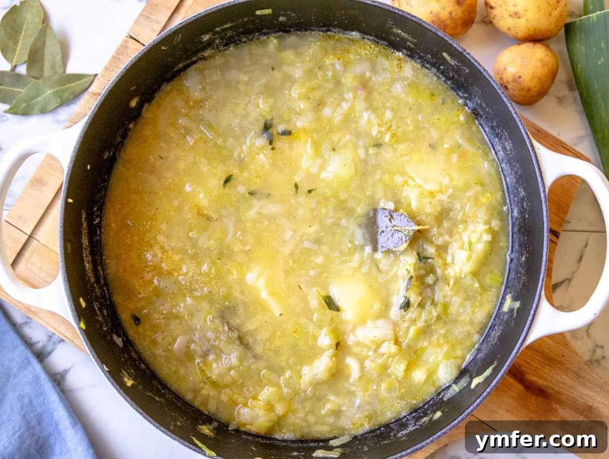 Naturally Creamy Potato Leek Soup with Skyr 5 Step 2 Potatoes simmering in vegetable broth with thyme and pepper in a pot.