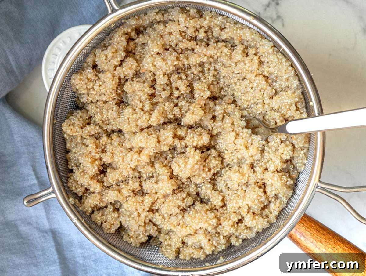 White quinoa cooking in a pot and cooling in a fine mesh strainer, step one for making a heart-healthy kale quinoa salad