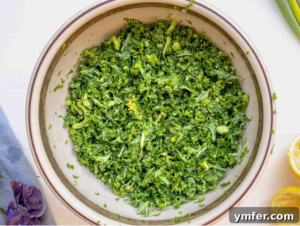 Massaged chopped kale with lemon and salt in a large bowl, softening the leaves for a nutritious anti-inflammatory salad