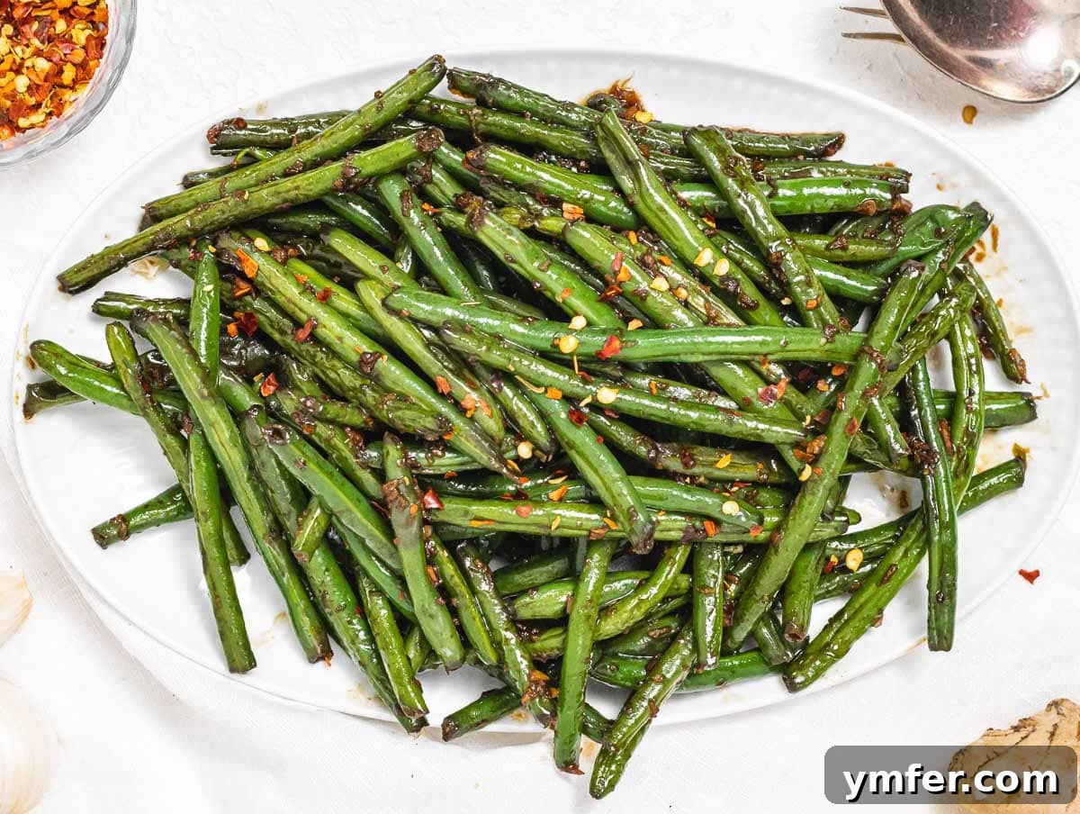 Flavorful Sautéed Green Beans 13 Sautéed green beans infused with Asian flavors, glistening with soy sauce and garnished with sesame seeds, served in a black bowl