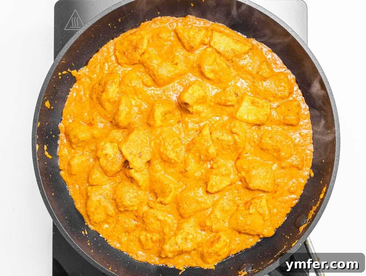 Velvety Vegan Butter Chicken 11 Creamy vegan butter chicken simmering gently in a pan, with the sauce thickening around the tofu.