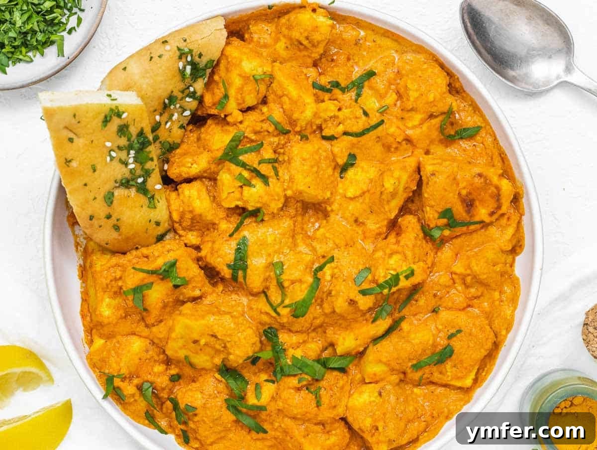 Velvety Vegan Butter Chicken 3 Close-up of Vegan Butter Chicken served with a piece of naan bread, highlighting the rich sauce and tender tofu.