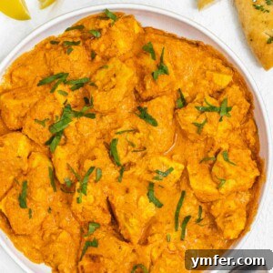 Velvety Vegan Butter Chicken 14 A white plate featuring a generous serving of Vegan Butter Chicken, garnished with fresh cilantro and a lemon wedge.