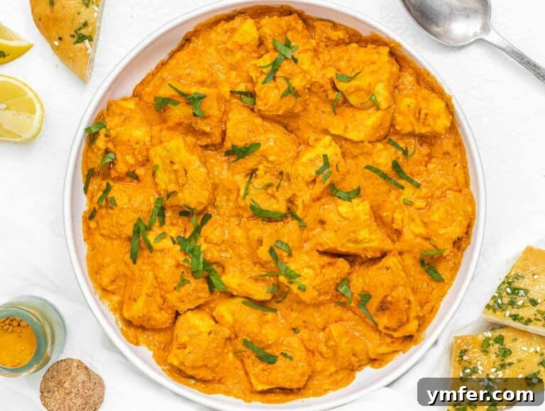 Velvety Vegan Butter Chicken 21 A bowl of finished Vegan Butter Chicken, beautifully garnished with fresh lemon and cilantro, ready to be served with bread.