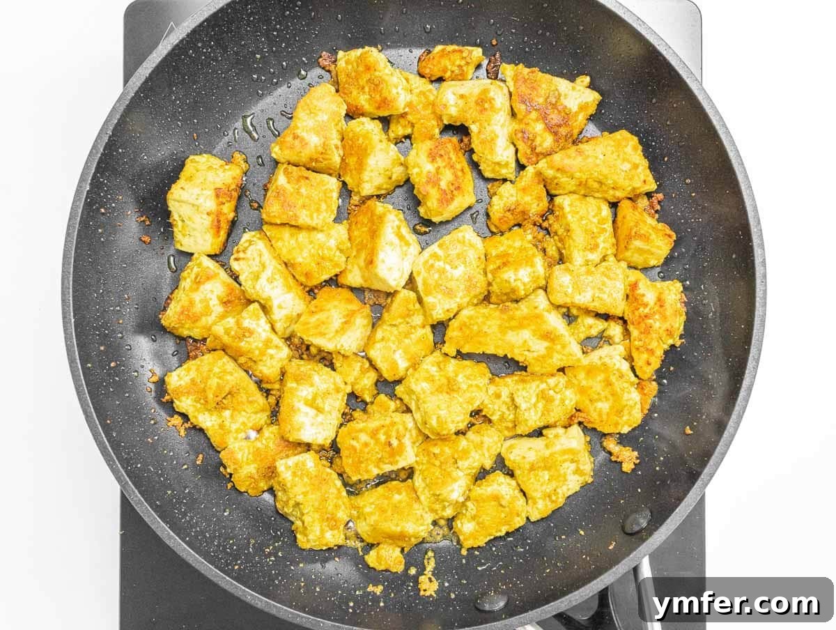 Velvety Vegan Butter Chicken 9 Golden brown marinated tofu pieces frying in a nonstick pan.