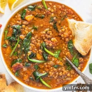 Lentil vegetable soup with spinach, a silver spoon and bread
