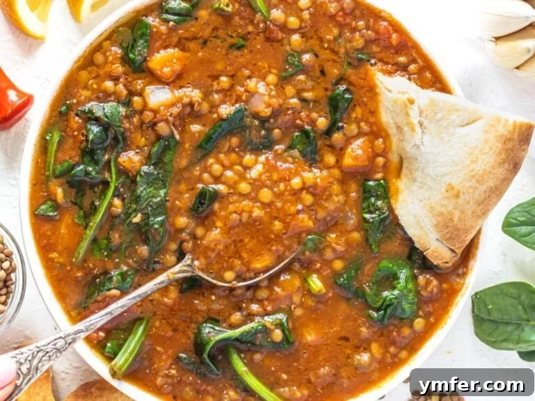 Easy lentil vegetable soup with pita bread and hand holding a silver spoon