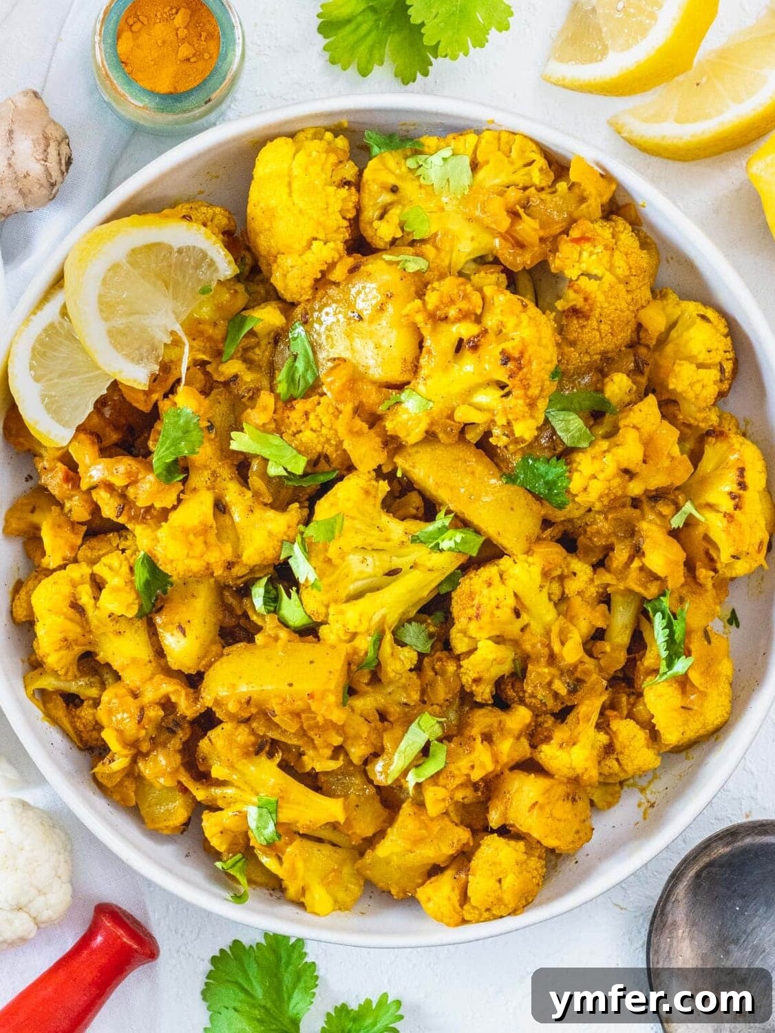 Aloo Gobi in a bowl with fresh lemon slices, ready to be served, highlighting its vibrant colors and rich texture.