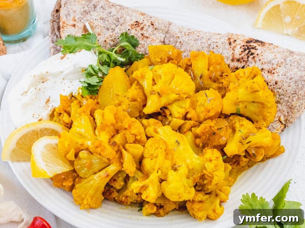 Aloo Gobi served in a bowl with fresh yogurt and a side of soft naan bread, creating a complete and delicious meal.