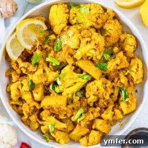 Aloo Gobi in a bowl with lemon slices, showcasing its inviting presentation.