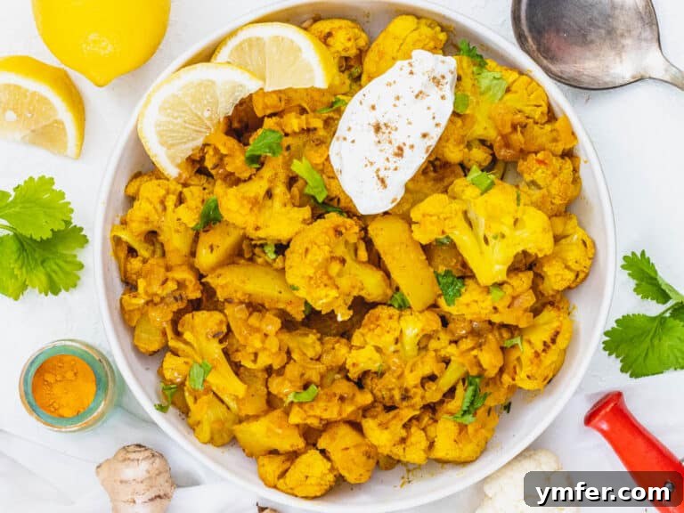 Aloo Gobi with yogurt and lemon wedges, ready to eat.