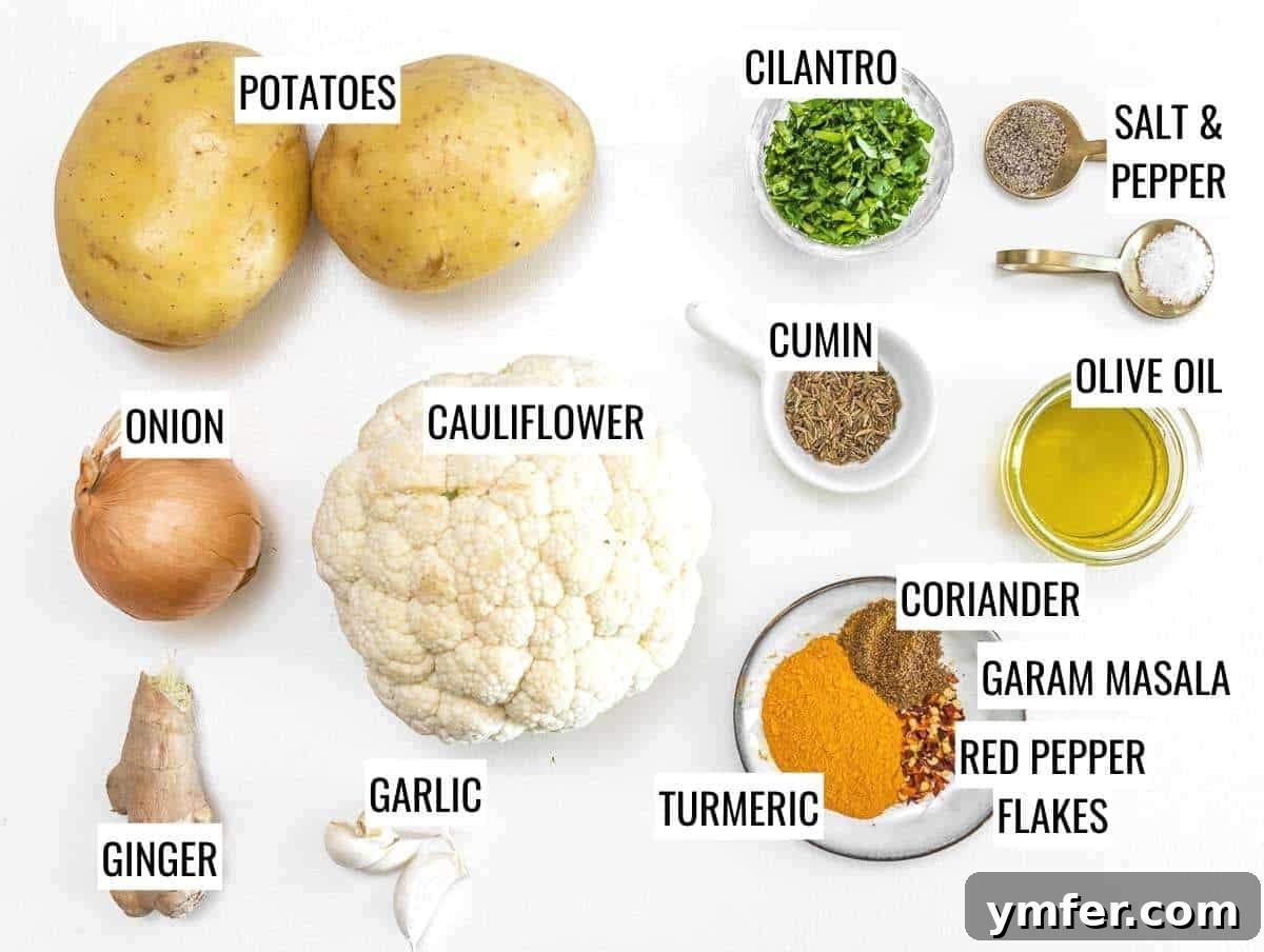 A vibrant selection of fresh ingredients laid out, including potatoes, cauliflower, onions, ginger, garlic, and an array of colorful spices for Aloo Gobi.