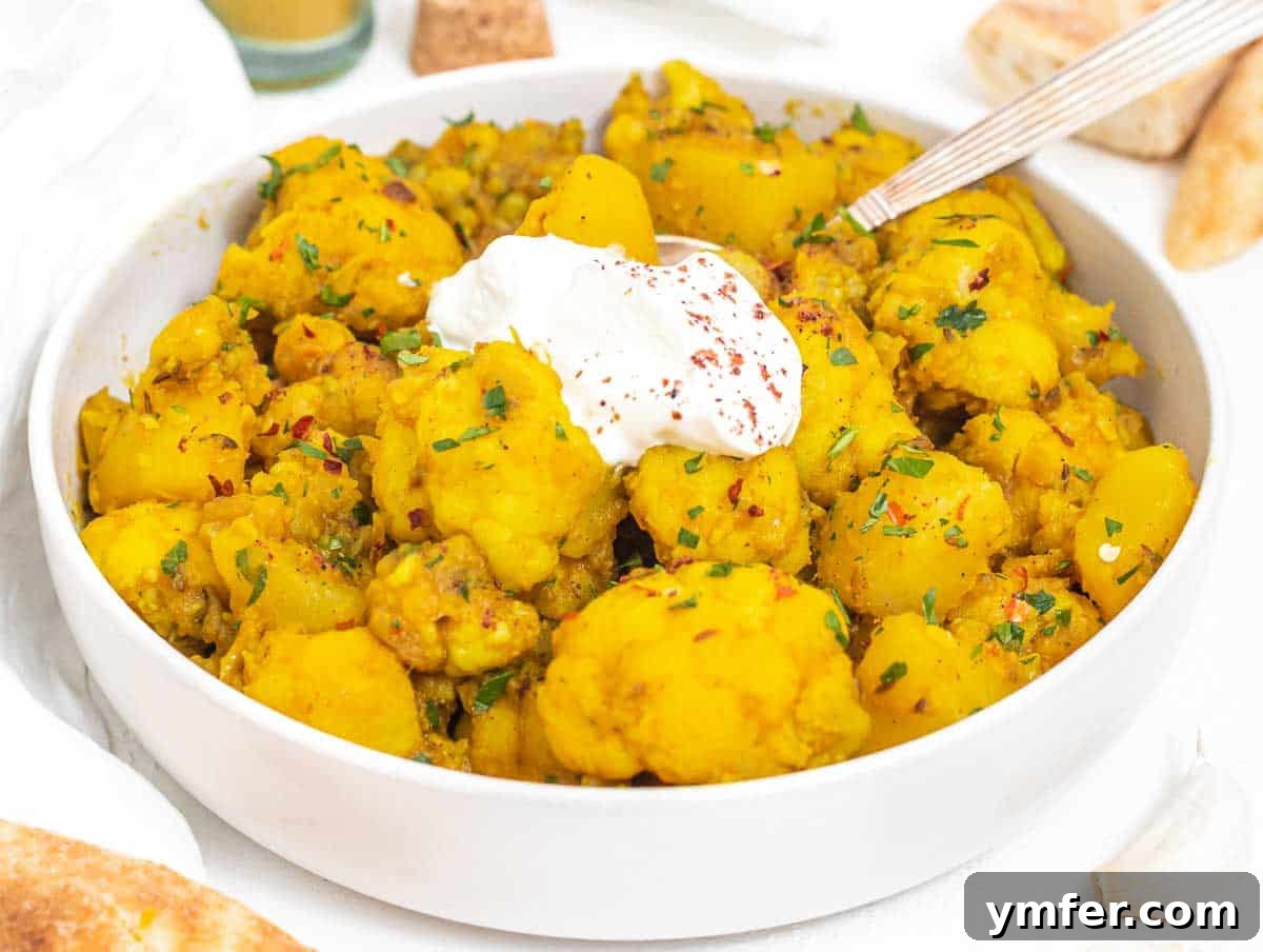 Aloo Gobi served in a rustic bowl with a dollop of yogurt on top, showcasing a hearty and comforting meal.