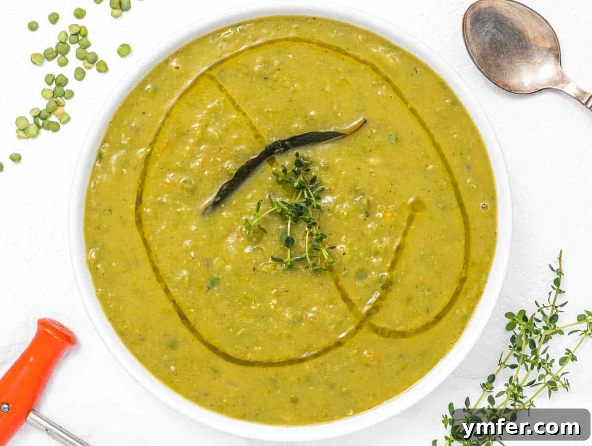 Golden Pea Goodness 11 A bowl of creamy split pea soup being served with a silver spoon, garnished with fresh herbs and a swirl of olive oil, ready to be enjoyed.