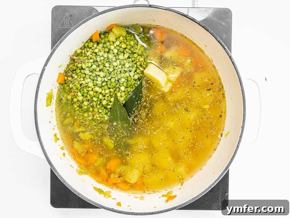 Golden Pea Goodness 8 Green split peas, vegetable broth, and aromatic herbs simmering in a large pot, beginning to cook down into a delicious and nourishing soup.