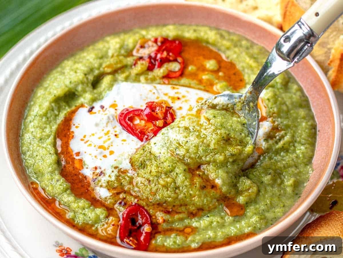 Effortless St Patricks Day Delights 12 A bowl of creamy broccoli soup with a spoon and a dollop of burrata cheese.