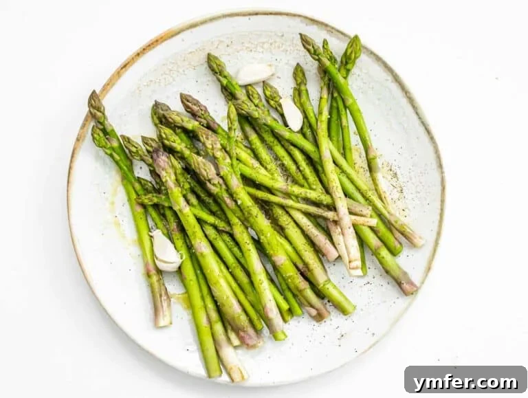 Effortless St Patricks Day Delights 21 Asparagus being tossed with olive oil, salt, and pepper in a bowl.