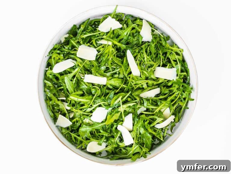 Rucola Rocket Greens with Citrus Vinaigrette 18 Arugula salad with parmesan cheese being added