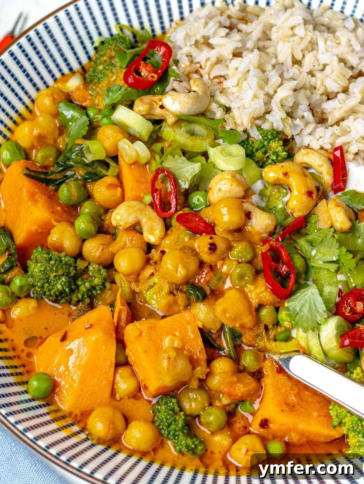 Vibrant Vegetable Curry 3 Vegetable curry served with basmati rice, garnished with fresh herbs and a lime wedge, in a blue bowl.