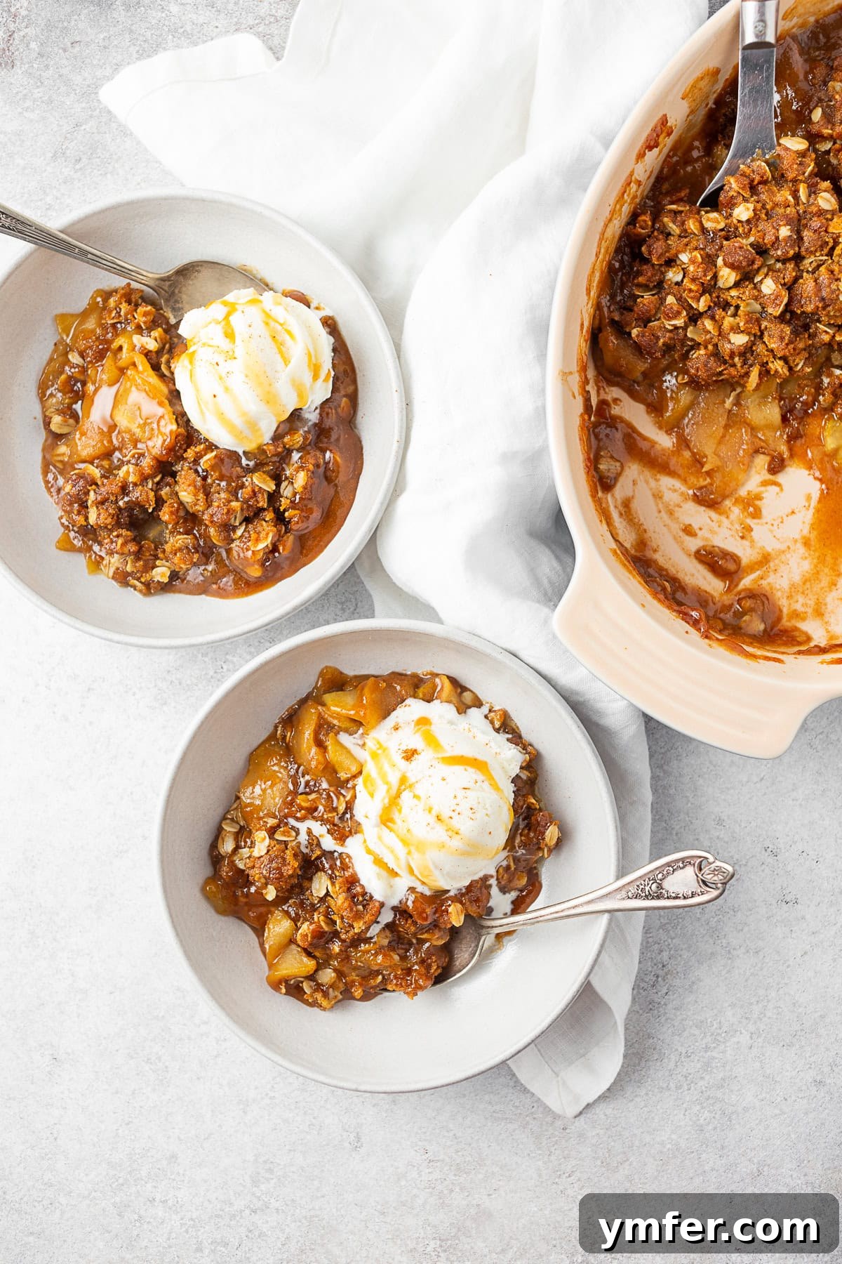 Sticky Caramel Apple Delight 5 Two bowls filled with caramel apple crisp and topped with ice cream, garnished for serving.
