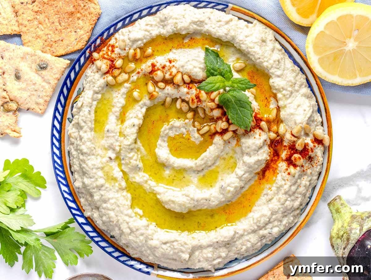Smoky Eggplant Tahini Dip 3 Mutabal on a blue plate with mint and pine nuts