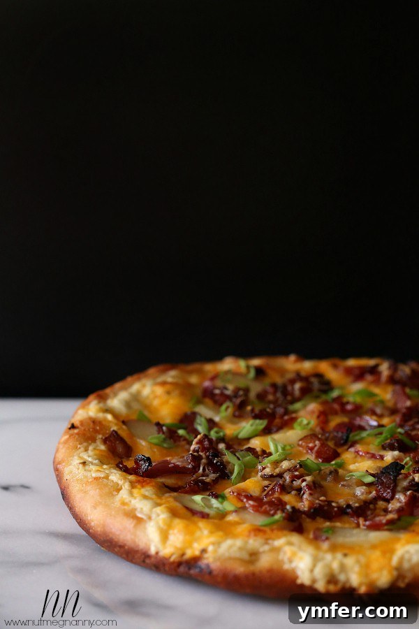 The Loaded Spud Pizza 4 A whole loaded baked potato pizza on a marble cutting board, ready to be sliced.