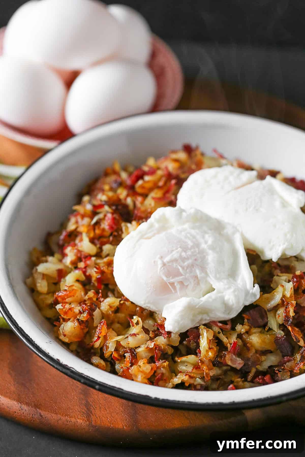 A close-up of golden-brown corned beef hash, garnished with fresh herbs and served alongside two perfectly poached eggs, ready to be enjoyed.