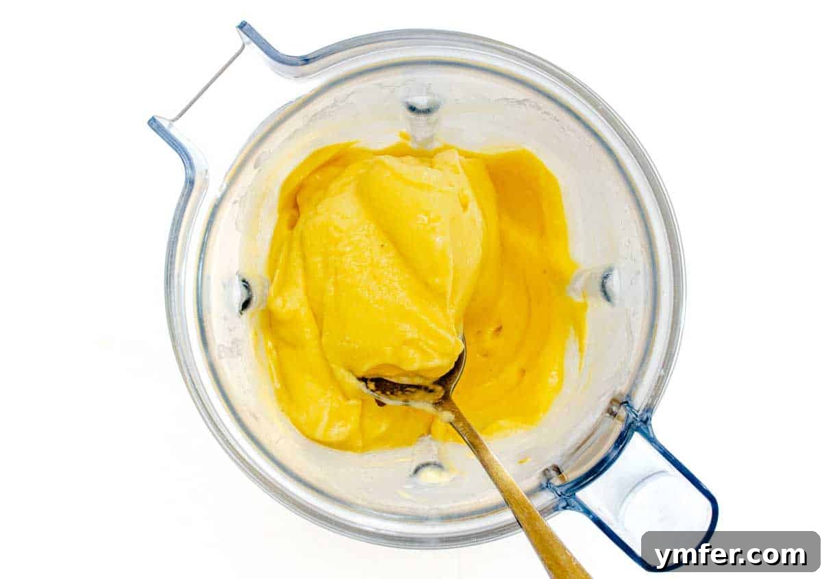 Frozen mango chunks, liquid, and sweetener being blended in a high-speed blender to create sorbet.