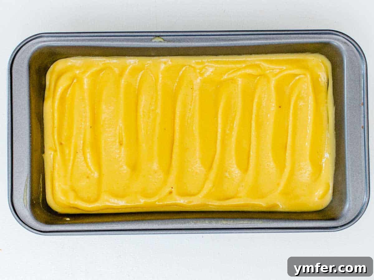 Mango sorbet mixture flattened in a loaf pan, ready for freezing.