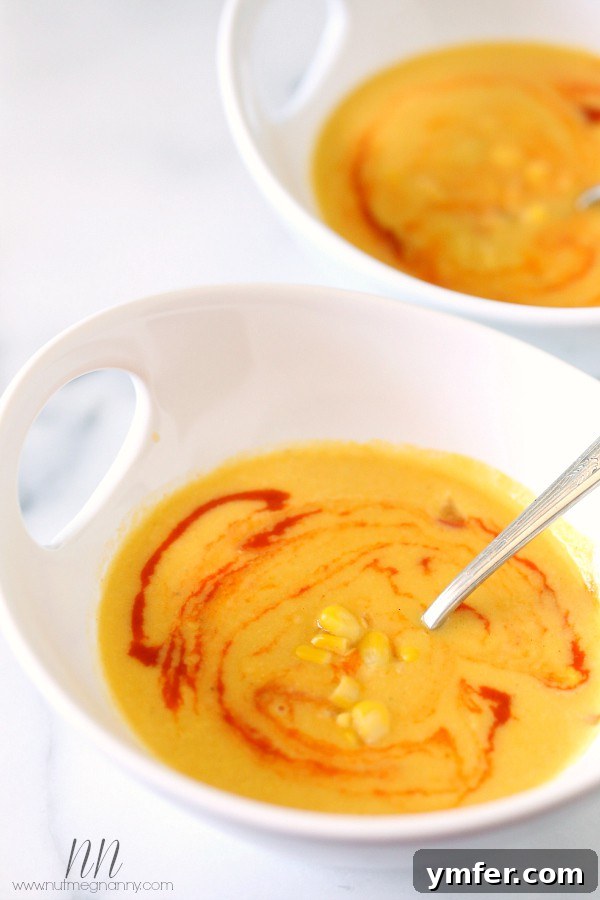 Smoky Sweet Corn Soup by Nutmeg Nanny A beautifully plated bowl of Smoky Sweet Corn Soup, topped with a creative swirl of sriracha