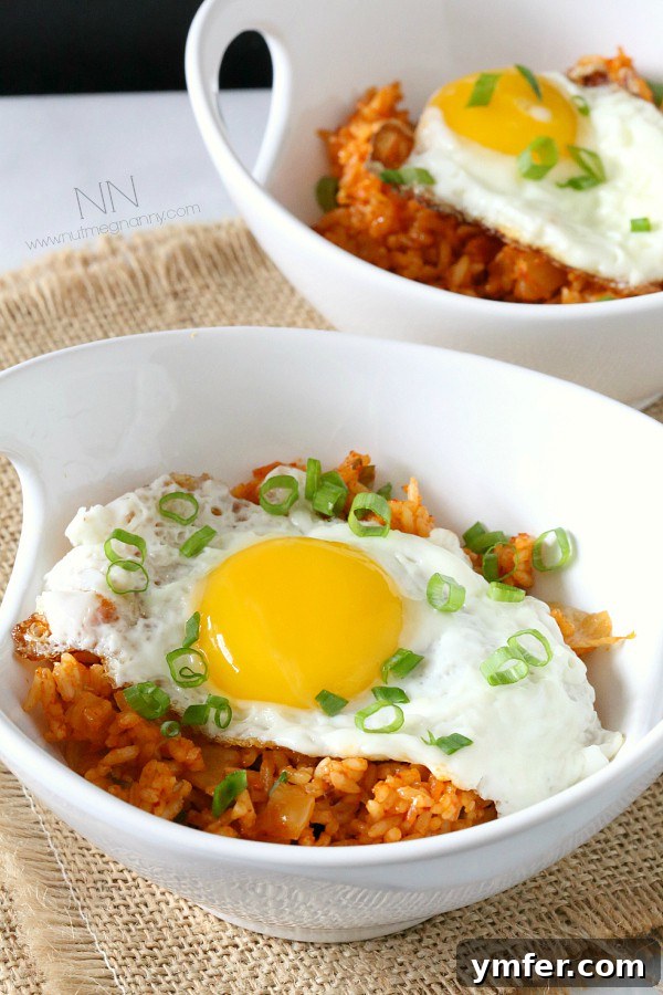 Kimchi Fried Rice by Nutmeg Nanny A vibrant bowl of Kimchi Fried Rice, garnished with fresh scallions and a perfectly fried egg.
