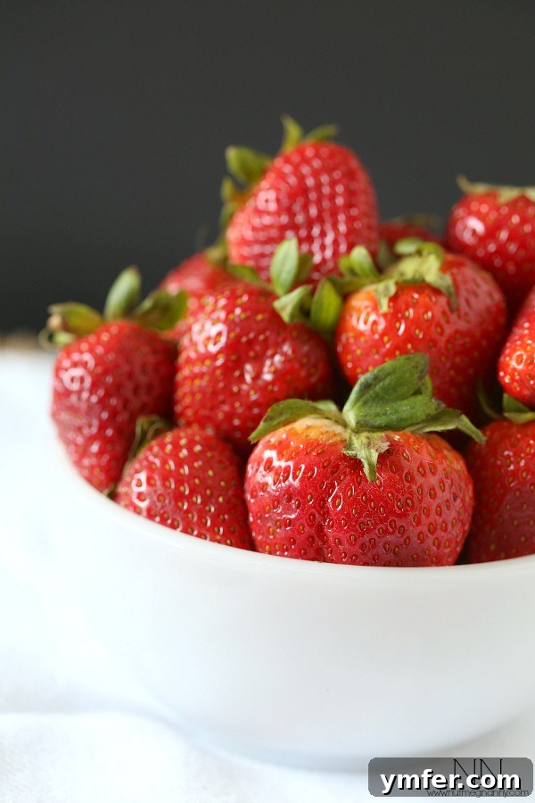 Summer Strawberry Chevre Quinoa Bowl 3 A bright red bowl overflowing with fresh, juicy strawberries, ready for preparation.