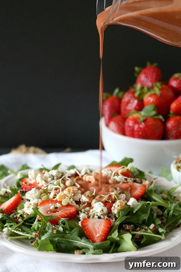 Summer Strawberry Chevre Quinoa Bowl 5 A rich, red strawberry dressing being generously poured over a vibrant quinoa salad.