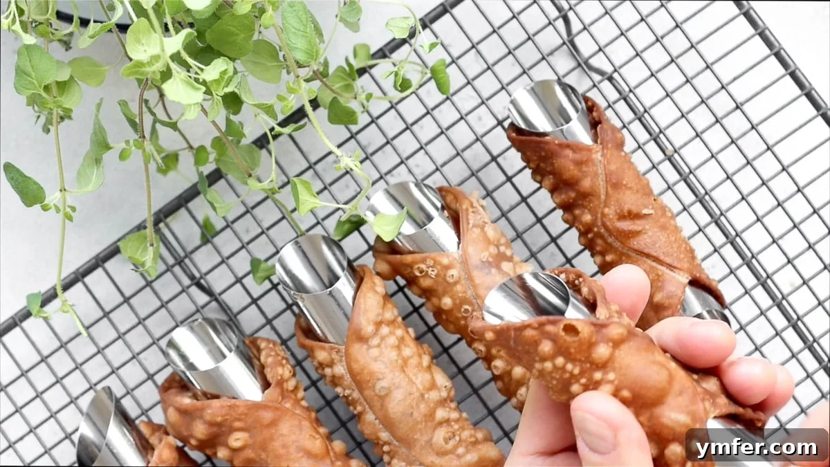 Carefully removing the metal tube from a cooled cannoli shell.