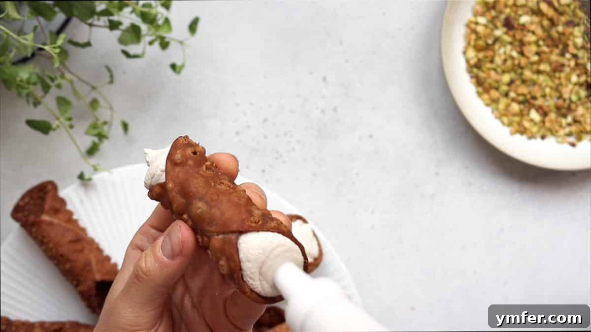 Piping the creamy vegan ricotta filling into a crispy cannoli shell.