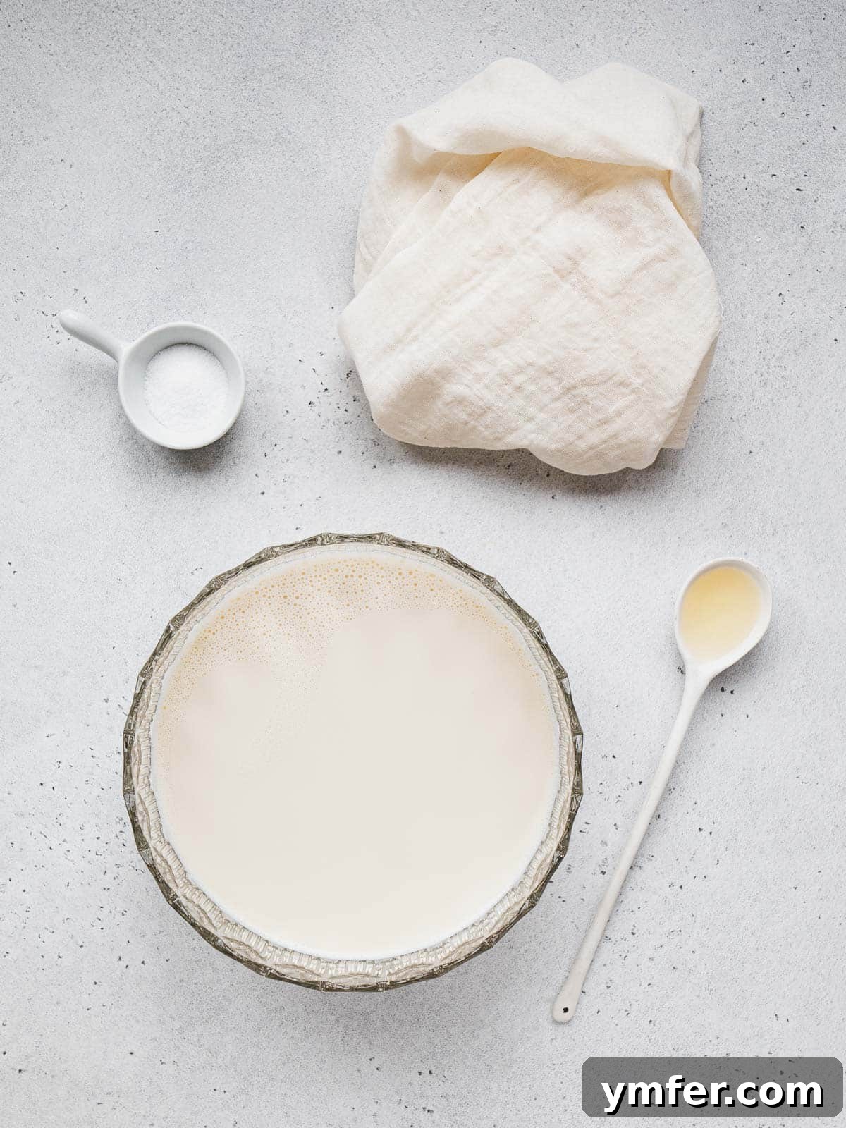 Equipment laid out for preparing vegan ricotta, including a cheesecloth and strainer.