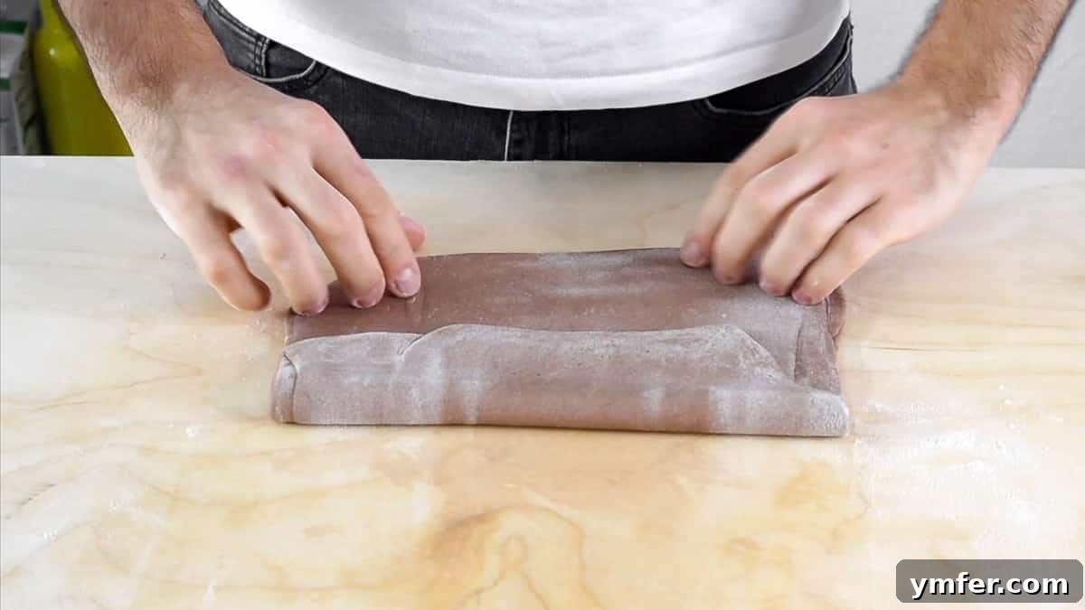 Folding the cannoli dough multiple times to create airy layers.